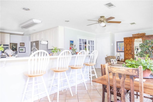 406 Saint Francis Rd, Eufaula, AL 36027 - kitchen featuring appliances with stainless steel finishes, a breakfast bar area, light tile patterned flooring, white cabinetry, and ceiling fan