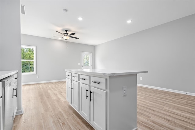 kitchen featuring white cabinets, ceiling fan, a center island, and light hardwood / wood-style flooring