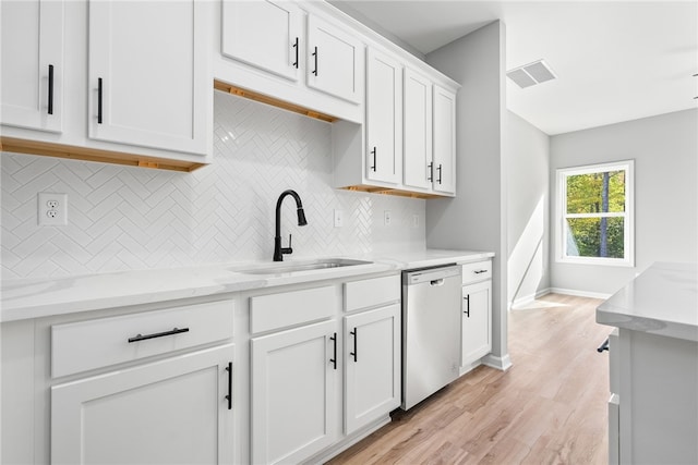 kitchen with dishwasher, white cabinets, sink, decorative backsplash, and light stone countertops