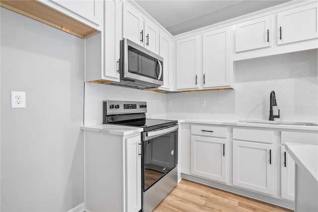 kitchen featuring white cabinets, decorative backsplash, stainless steel appliances, and sink