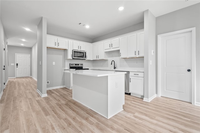 kitchen featuring white cabinets, a kitchen island, sink, and stainless steel appliances