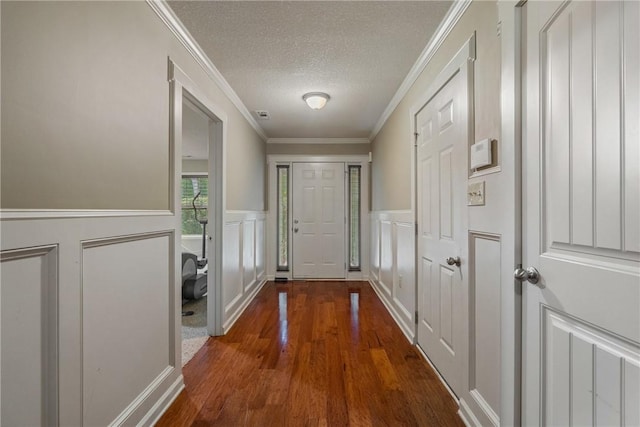 doorway with ornamental molding, dark hardwood / wood-style flooring, and a textured ceiling