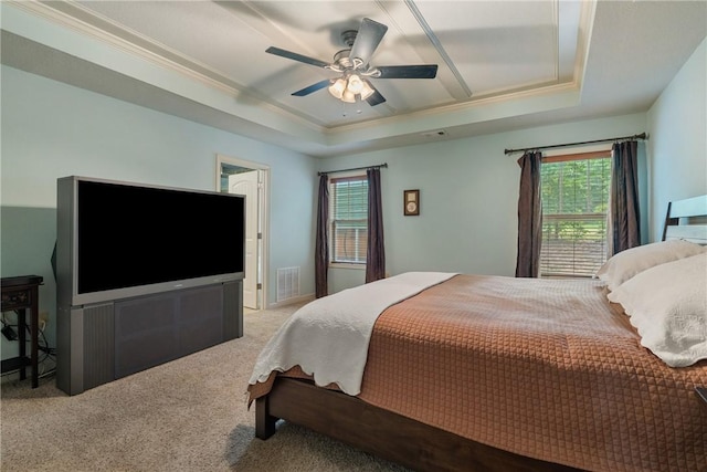 bedroom featuring ceiling fan, a tray ceiling, light carpet, and multiple windows