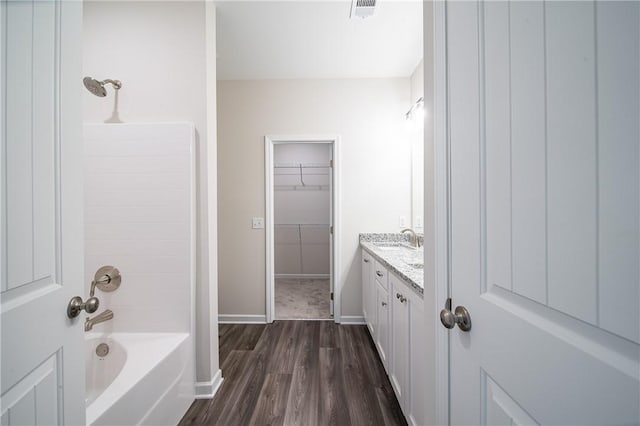 full bath with a spacious closet, visible vents, baseboards, wood finished floors, and vanity