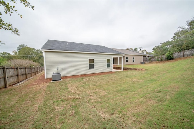 back of house featuring central air condition unit, a lawn, and fence