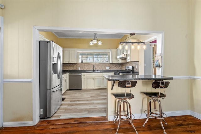 kitchen with a sink, appliances with stainless steel finishes, a kitchen bar, and white cabinetry