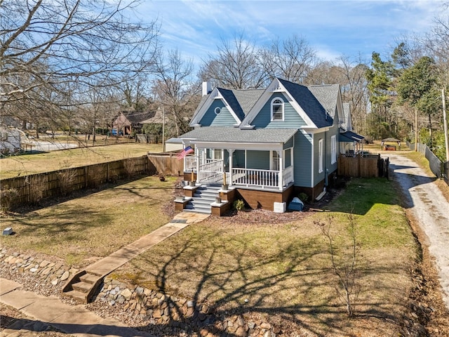 bungalow featuring a chimney, covered porch, fence private yard, driveway, and a front lawn