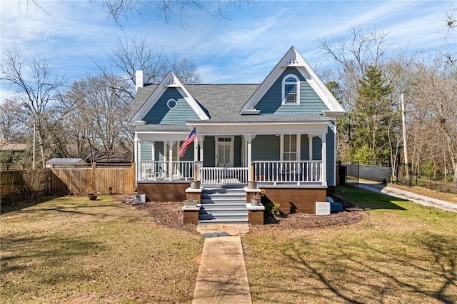 view of front facade featuring roof with shingles, a chimney, a porch, fence, and a front lawn