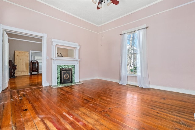 unfurnished living room with crown molding, baseboards, wood finished floors, and a tile fireplace