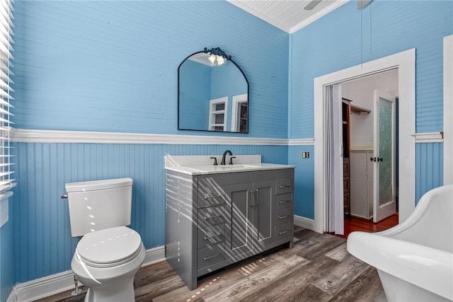 bathroom featuring a freestanding bath, vanity, toilet, and wood finished floors