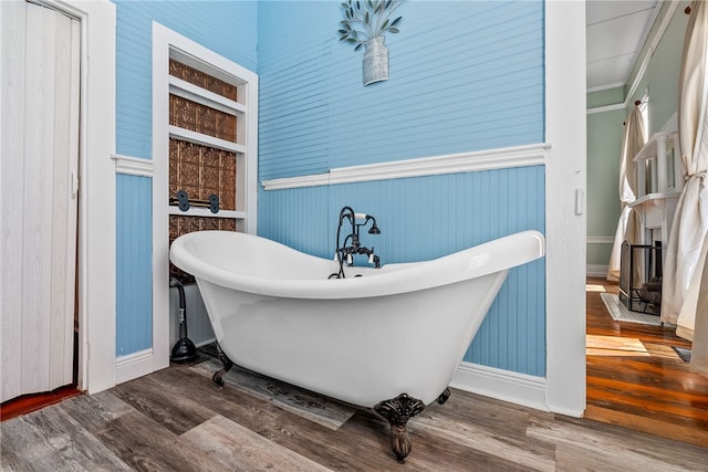 full bathroom with a fireplace, a soaking tub, and wood finished floors