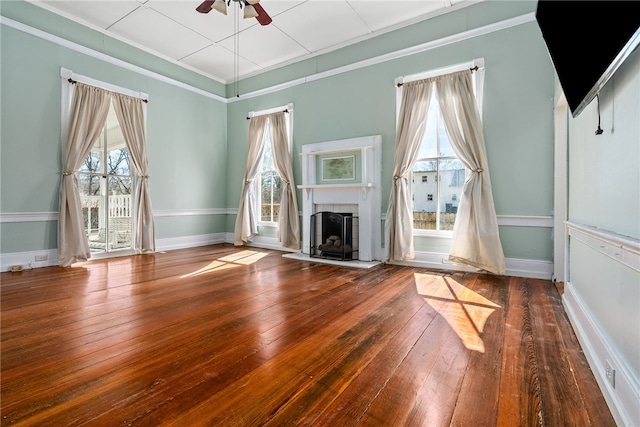 unfurnished living room with a wealth of natural light, wood finished floors, a fireplace, and ceiling fan