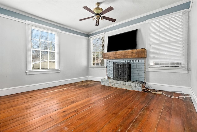 unfurnished living room with a healthy amount of sunlight, a fireplace, crown molding, and wood finished floors