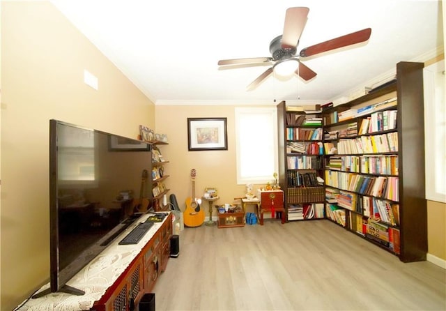 interior space featuring ceiling fan, crown molding, and light wood-type flooring