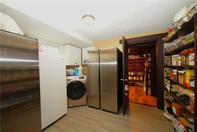 washroom with light hardwood / wood-style floors, cabinets, and washer / dryer