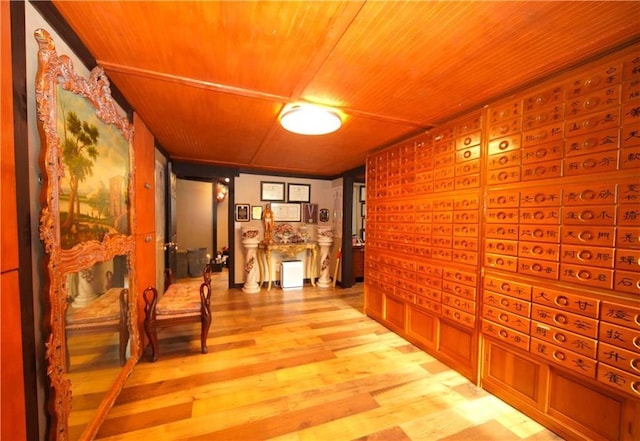 corridor with light hardwood / wood-style flooring and wood ceiling