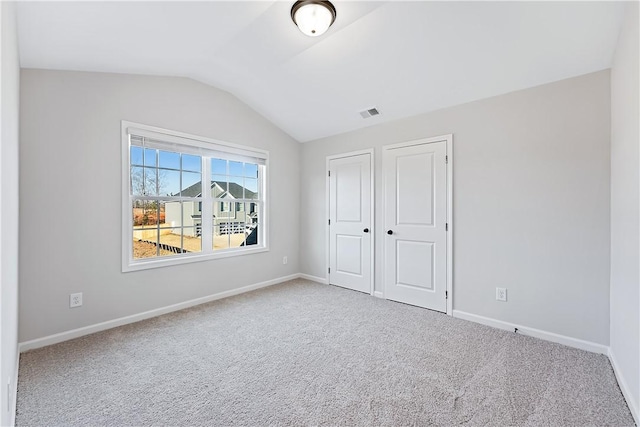 unfurnished bedroom featuring carpet flooring, lofted ceiling, and a closet