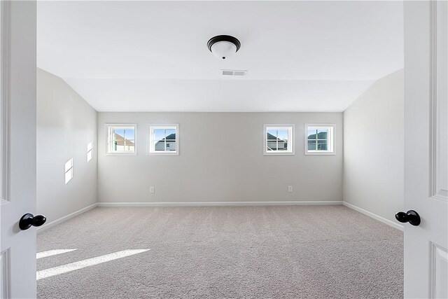 empty room featuring light colored carpet, plenty of natural light, and lofted ceiling