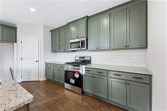 kitchen with backsplash, dark hardwood / wood-style floors, stainless steel appliances, and green cabinetry