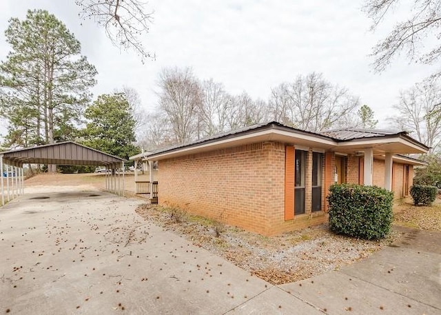 view of side of home featuring a detached carport, brick siding, and driveway