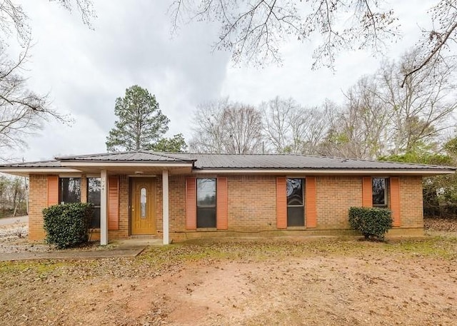 view of front of property featuring brick siding and metal roof