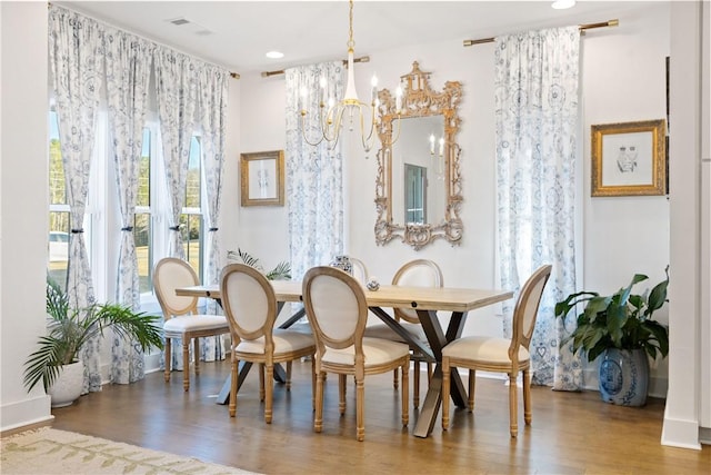 dining room featuring wood-type flooring, a wealth of natural light, and a chandelier