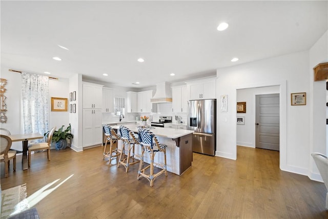 kitchen featuring premium range hood, a kitchen island, white cabinetry, a kitchen breakfast bar, and stainless steel appliances