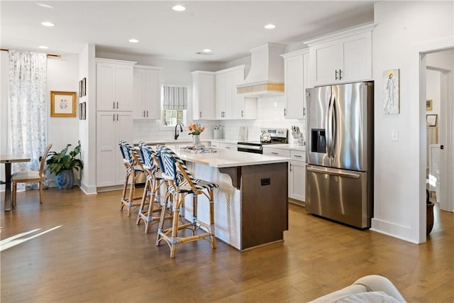 kitchen featuring white cabinetry, a kitchen island, premium range hood, and appliances with stainless steel finishes