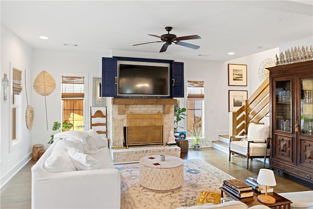 living room with a brick fireplace, hardwood / wood-style floors, and ceiling fan