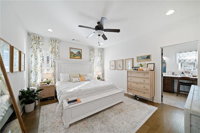 bedroom featuring ceiling fan, ensuite bath, and dark hardwood / wood-style flooring