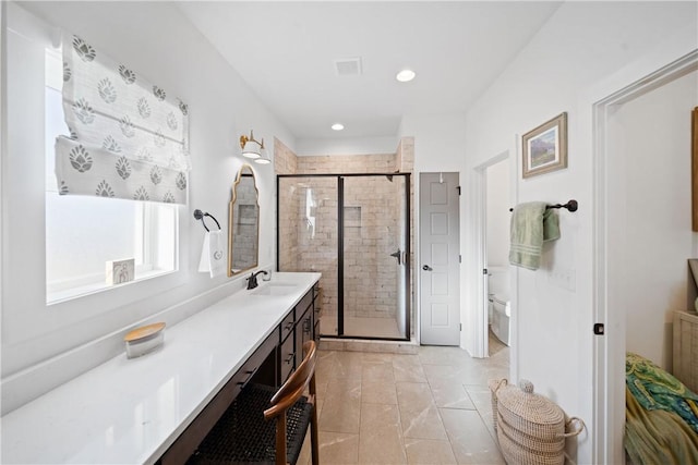 bathroom featuring a shower with door, vanity, tile patterned floors, and toilet