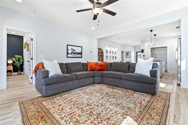 living room featuring a ceiling fan, recessed lighting, light wood-style floors, and baseboards