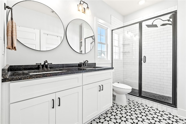 full bathroom featuring double vanity, toilet, a stall shower, and a sink