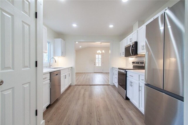762 Lee Road 197, Phenix City, AL 36870 - kitchen featuring light wood finished floors, a sink, light countertops, vaulted ceiling, and appliances with stainless steel finishes