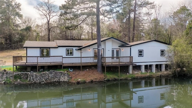 rear view of property with a shingled roof and a deck with water view