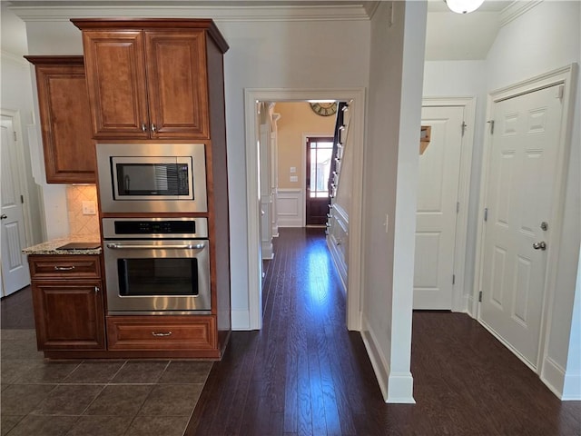 kitchen with tasteful backsplash, appliances with stainless steel finishes, dark wood-type flooring, and crown molding