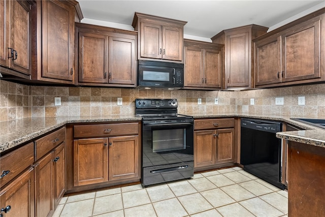 kitchen with dark stone counters, decorative backsplash, light tile patterned floors, and black appliances