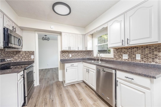 kitchen with appliances with stainless steel finishes, white cabinetry, and sink