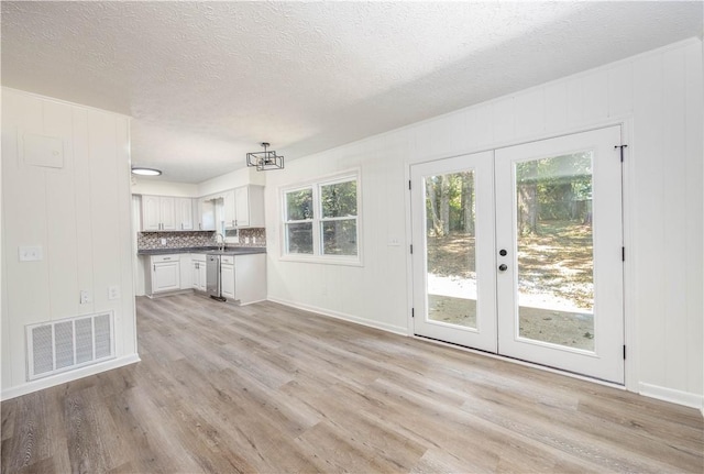 interior space featuring sink, french doors, a textured ceiling, and light wood-type flooring