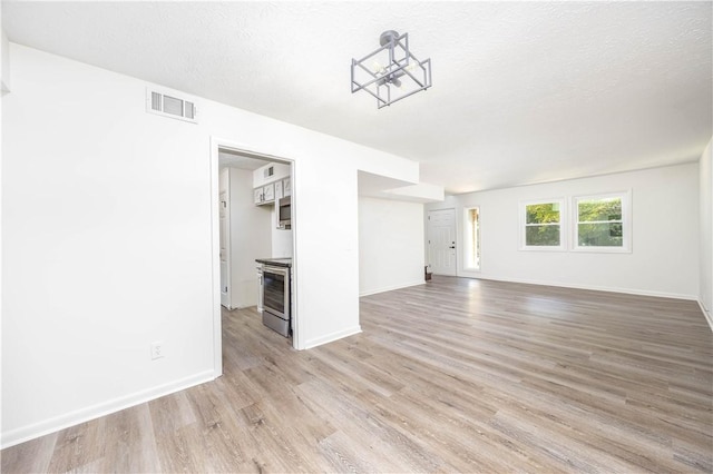 unfurnished living room with a textured ceiling, light hardwood / wood-style floors, and a notable chandelier