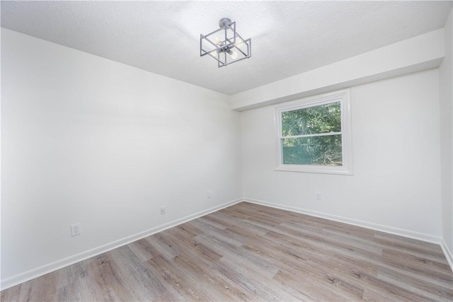 empty room featuring a textured ceiling and light hardwood / wood-style flooring