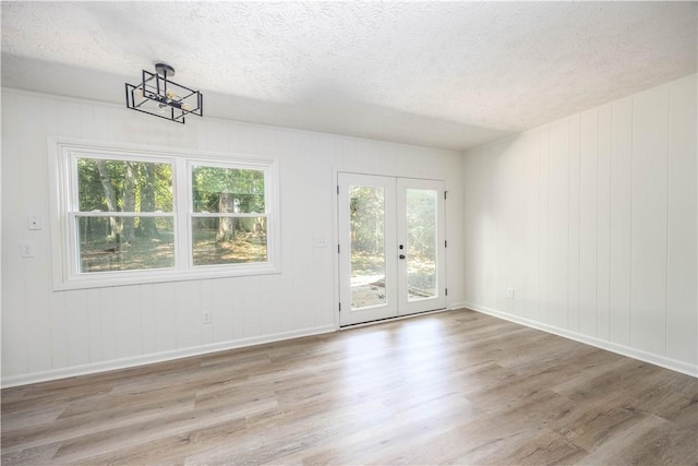 empty room with french doors, a textured ceiling, and hardwood / wood-style flooring