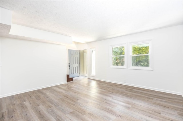 spare room featuring a textured ceiling and light wood-type flooring