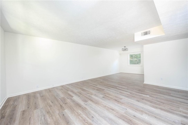 spare room with a textured ceiling and light wood-type flooring