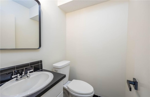 bathroom with vanity, toilet, and backsplash