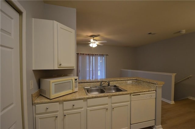 kitchen featuring light countertops, a peninsula, white cabinets, white appliances, and a sink