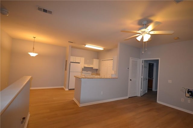 kitchen featuring visible vents, light wood-style flooring, freestanding refrigerator, white cabinets, and stove