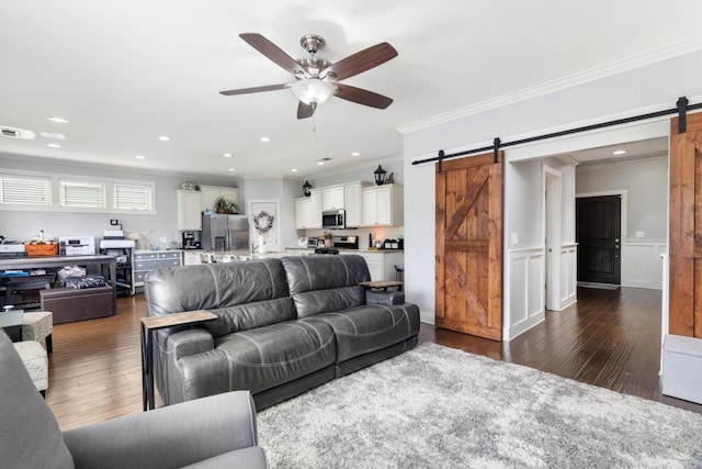 living room featuring crown molding, a barn door, dark wood-type flooring, and ceiling fan