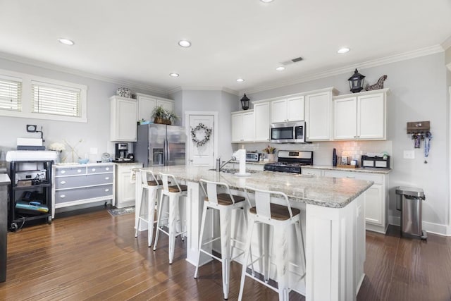 kitchen with a kitchen island with sink, sink, white cabinets, and appliances with stainless steel finishes