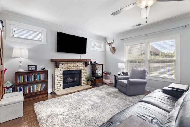 living room featuring crown molding, a fireplace, ceiling fan, and hardwood / wood-style flooring